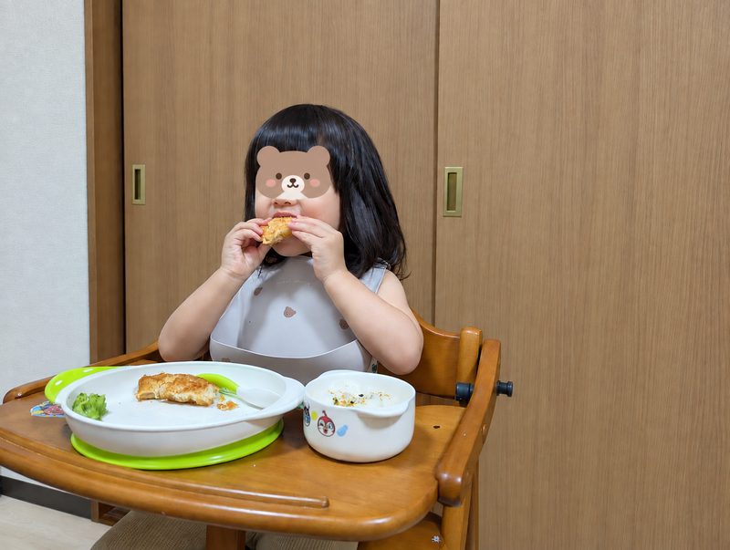モグモの白身魚フライを手づかみで食べる2歳の娘