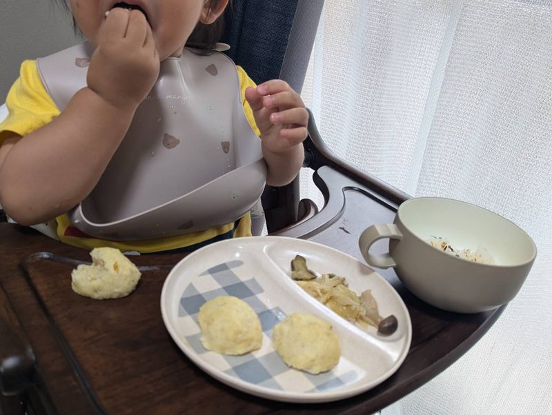 1歳半ごろの息子がお魚入り豆腐ハンバーグをくずしながら口に運んでいる様子